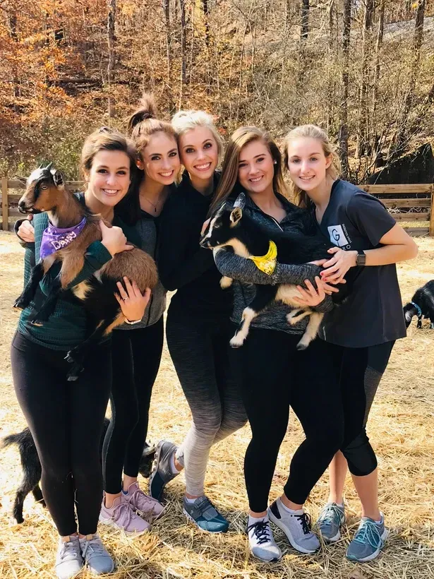 A group of women are standing next to each other holding goats.