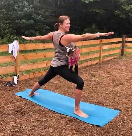 A woman is practicing yoga with a dog in her arms