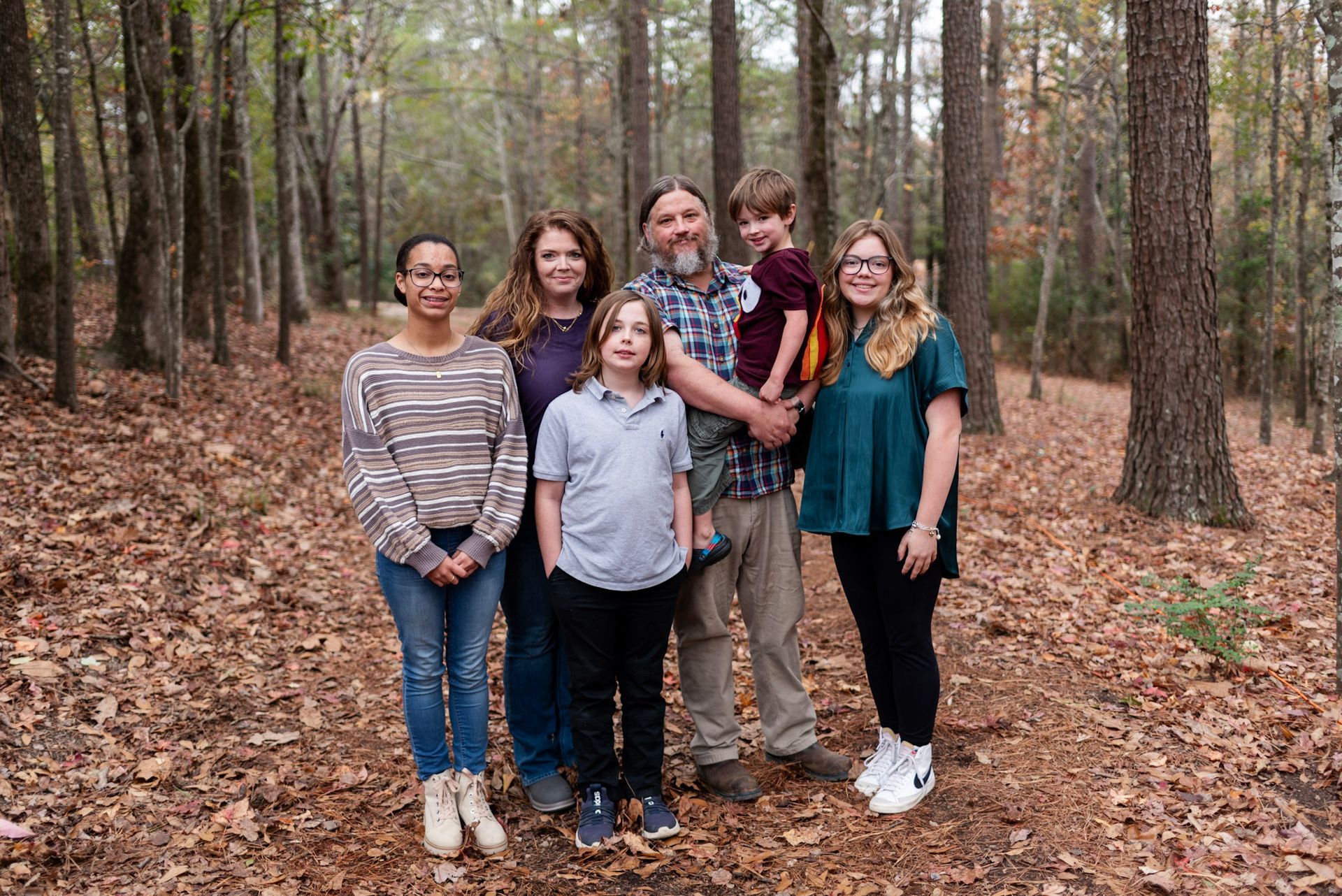 A family is posing for a picture in the woods.