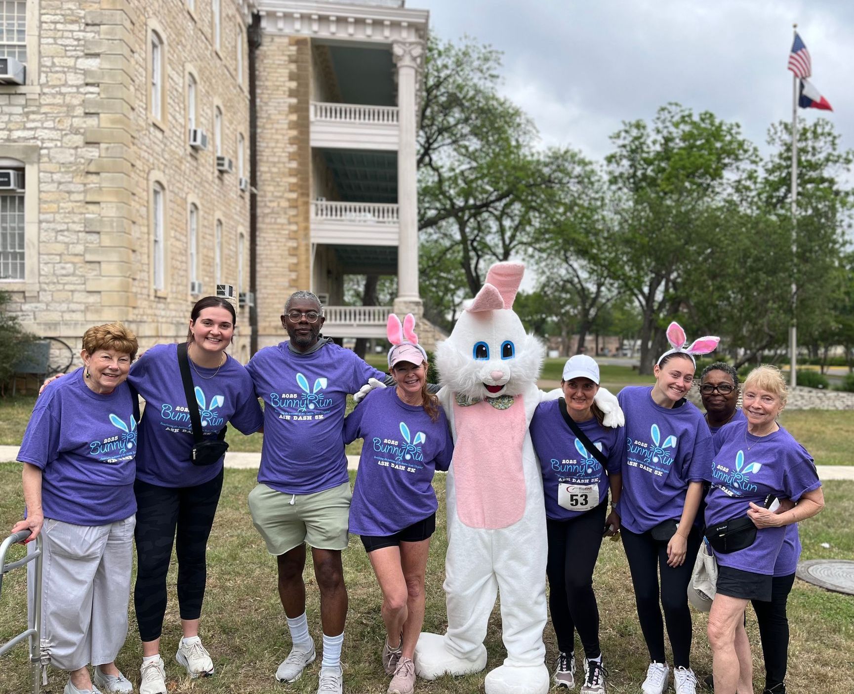A group of people in purple shirts with an Easter bunny