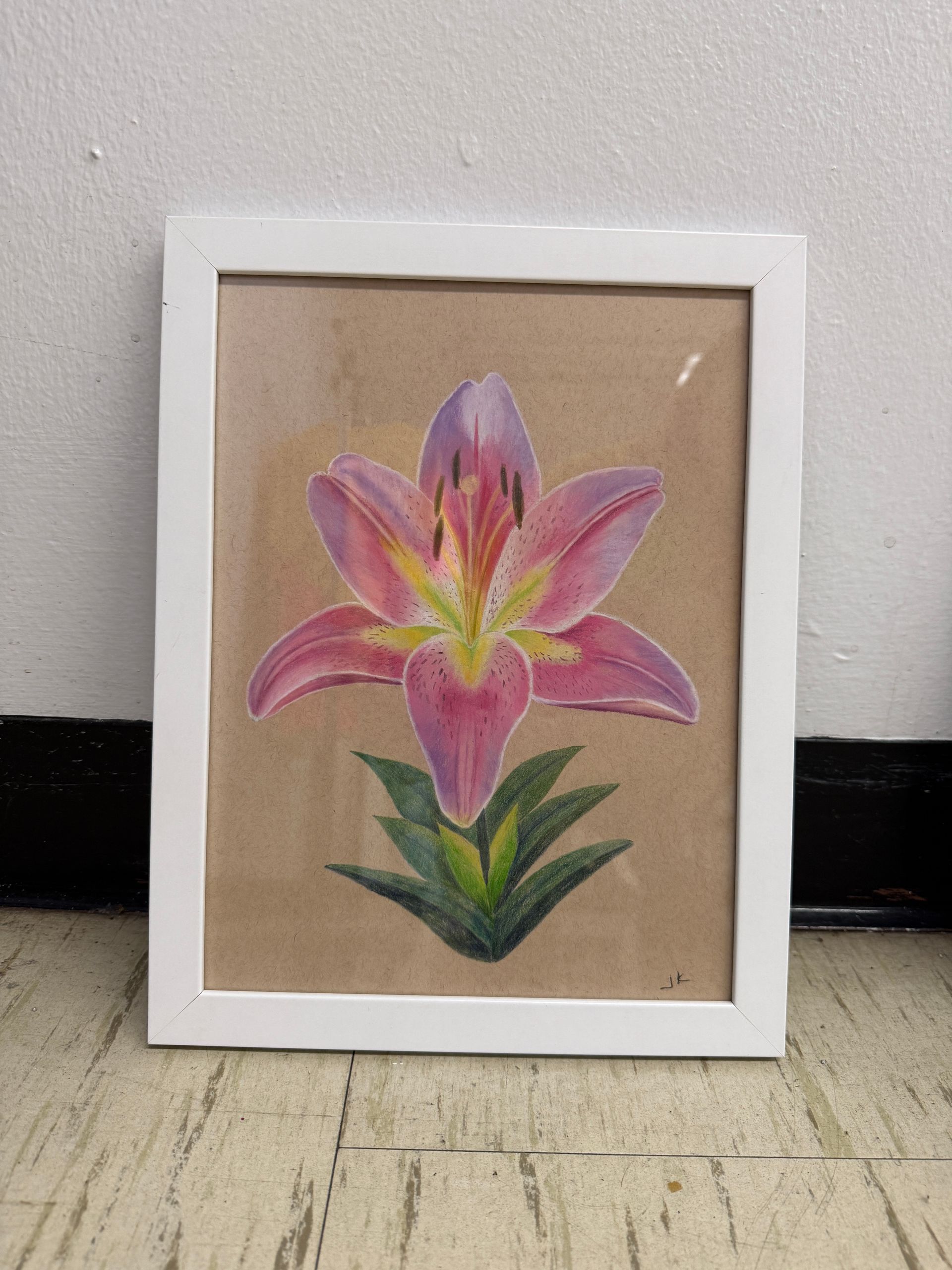 Framed watercolor painting of a pink lily flower with green leaves on a brown background.