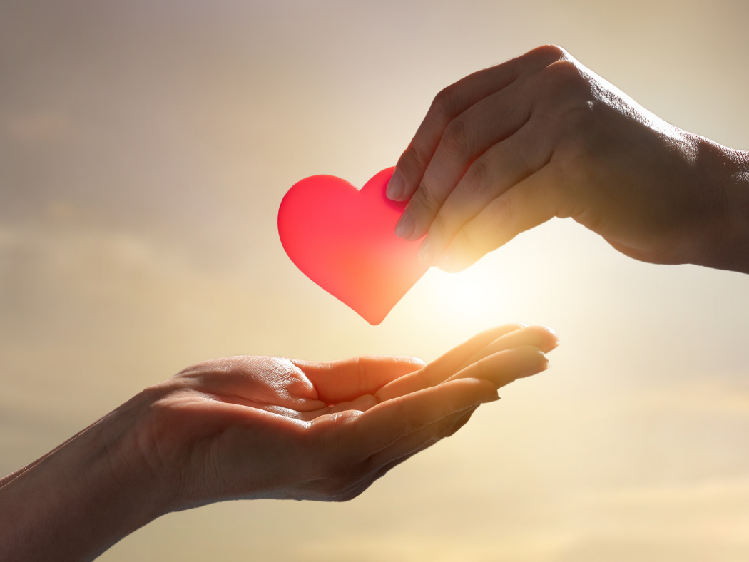 A person is giving a red heart to another person.