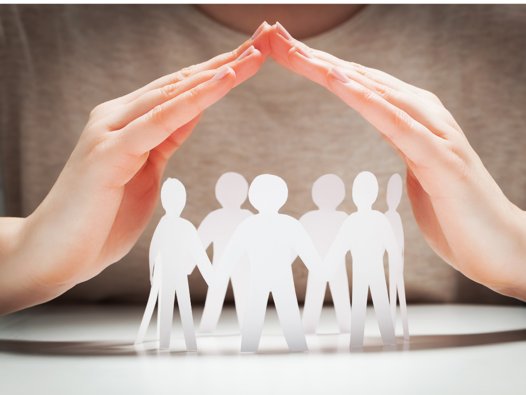 A woman is covering a group of paper people with her hands