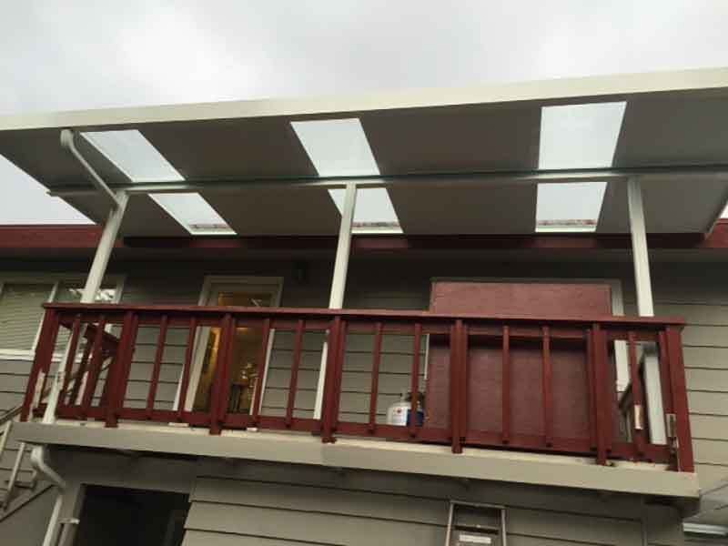 A Balcony With A White Roof And A Red Railing On The Side Of A House — Kirkland, WA — Action Installations LLC