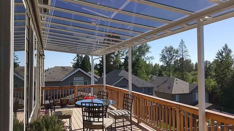 A Deck With A Table And Chairs Under A Clear Roof — Kirkland, WA — Action Installations LLC