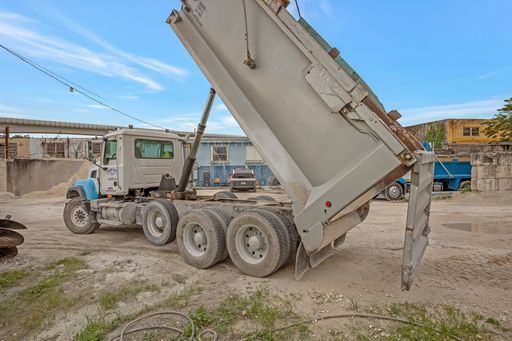 A dump truck is parked in a dirt lot with its bed up.
