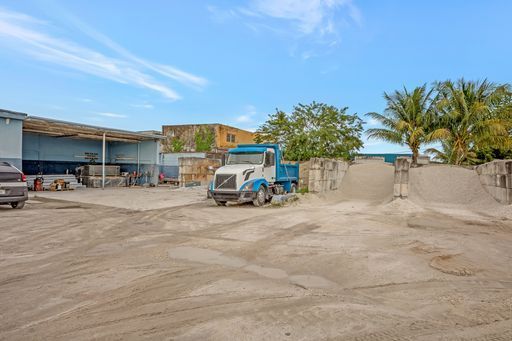 A blue and white truck is parked in a dirt lot.
