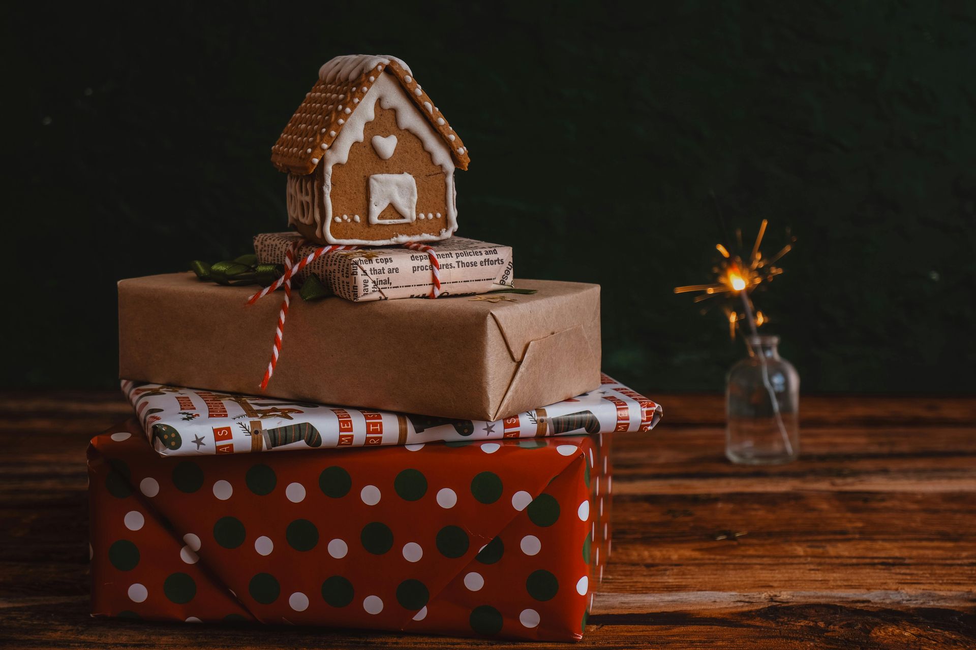 A gingerbread house is sitting on top of a stack of Christmas presents.