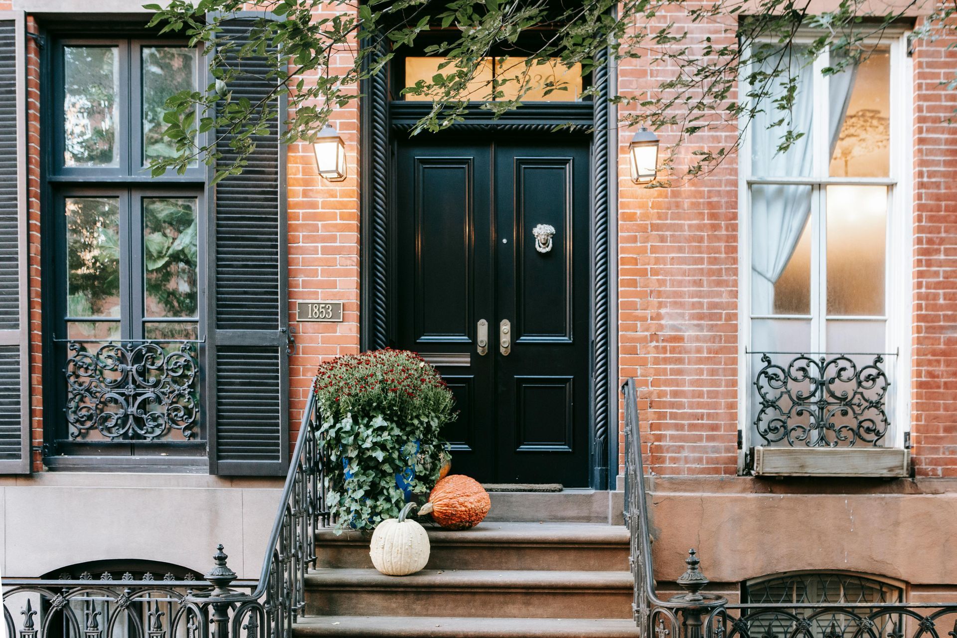 A brick building with a black door and pumpkins on the steps.