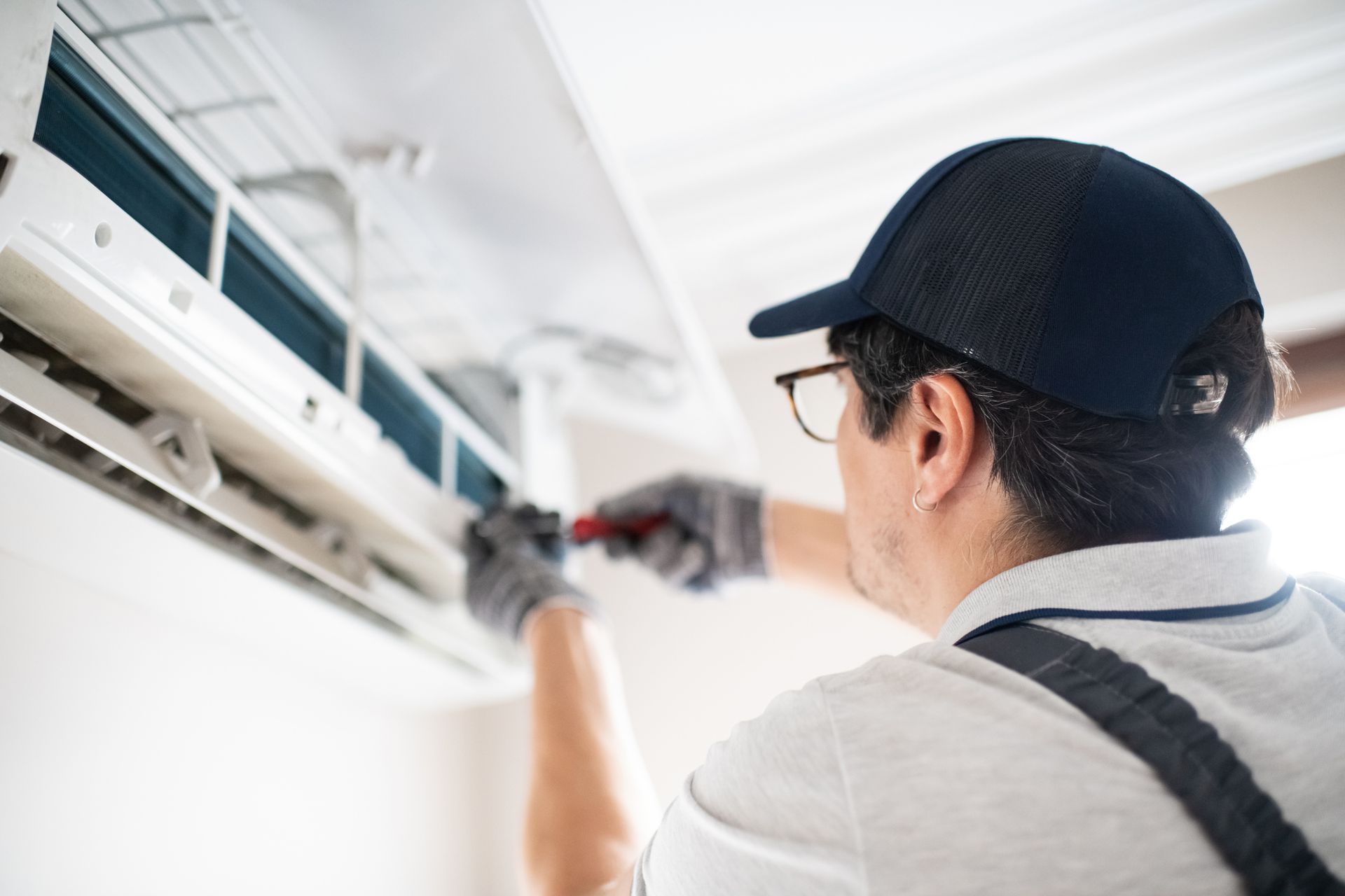 Technician performing AC repair service at home with screwdriver.