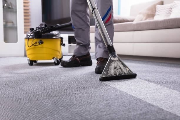 Person vacuuming a carpet with an industrial cleaner.