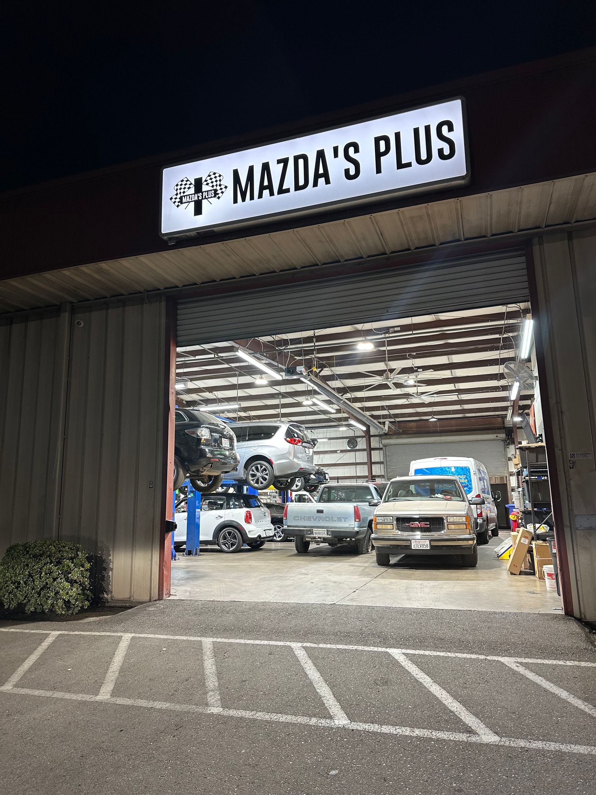Group of seven people posing outdoors in front of trees. Most wear blue work shirts.