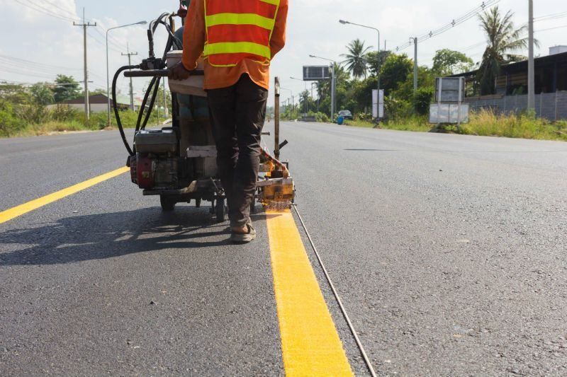 A man is painting a yellow line on the road.