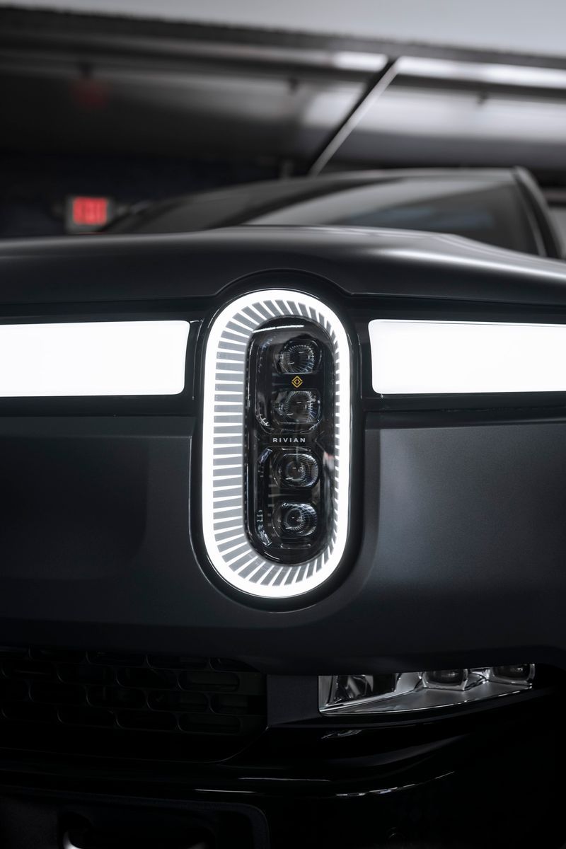 A close up of the front of a black car with a light on it.