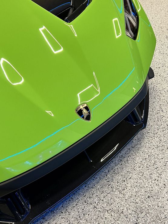 A green lamborghini huracan is parked in a garage.