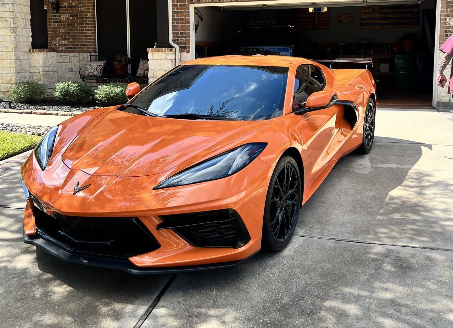 An orange sports car is parked in front of a garage.