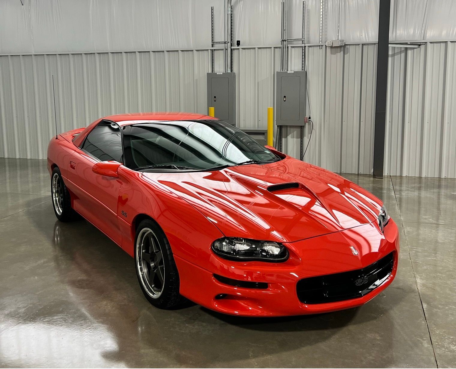 A red chevrolet camaro is parked in a garage.