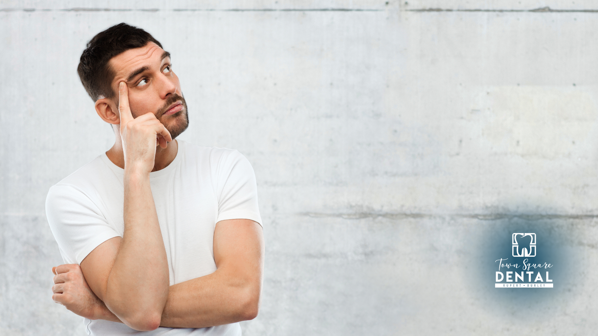 A man in a white shirt is thinking with his hand on his chin.