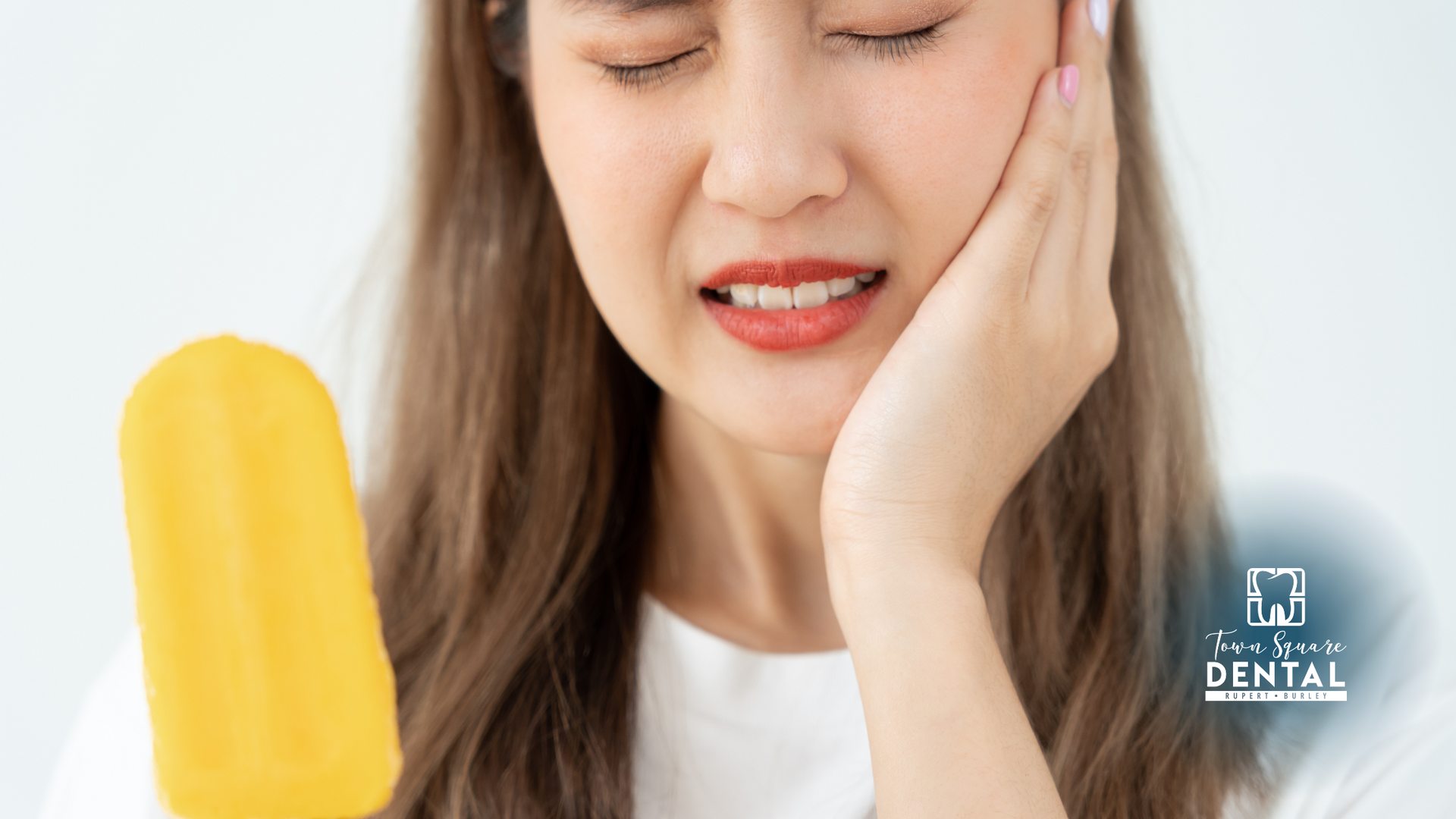 A woman is holding her face in pain while holding an ice cream cone.