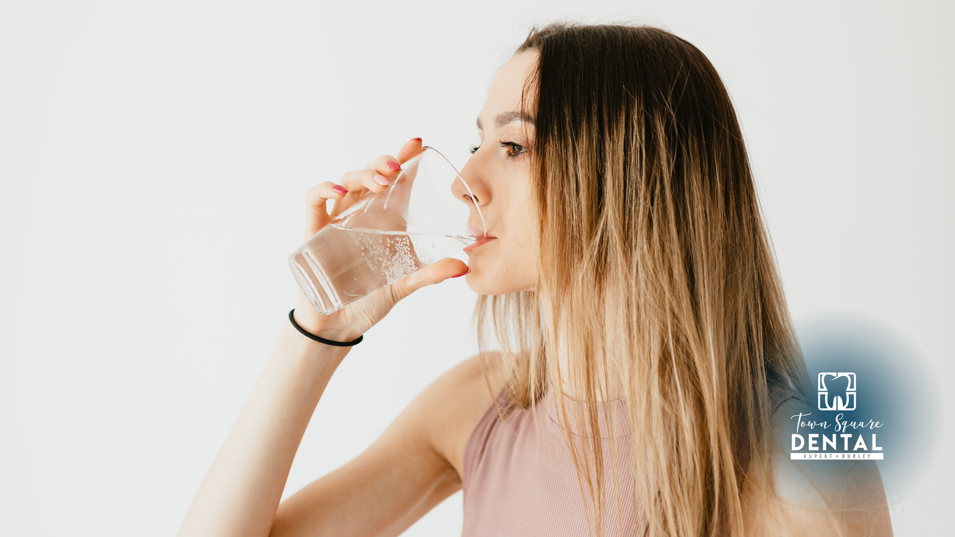A woman is drinking a glass of water.