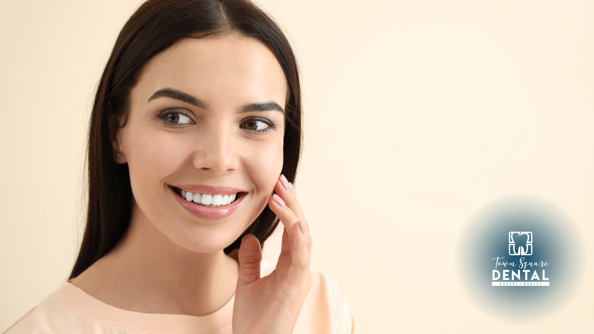 Woman with a bright smile, touching her cheek, against a light background.