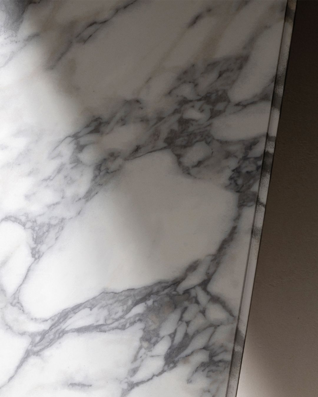 White marble countertop with gray veining, partially obscured by shadow.