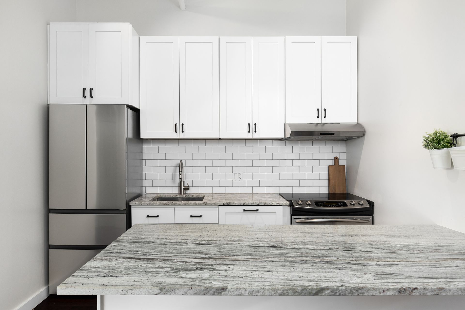 Small white kitchen with stainless steel appliances, white cabinets, and granite countertop.