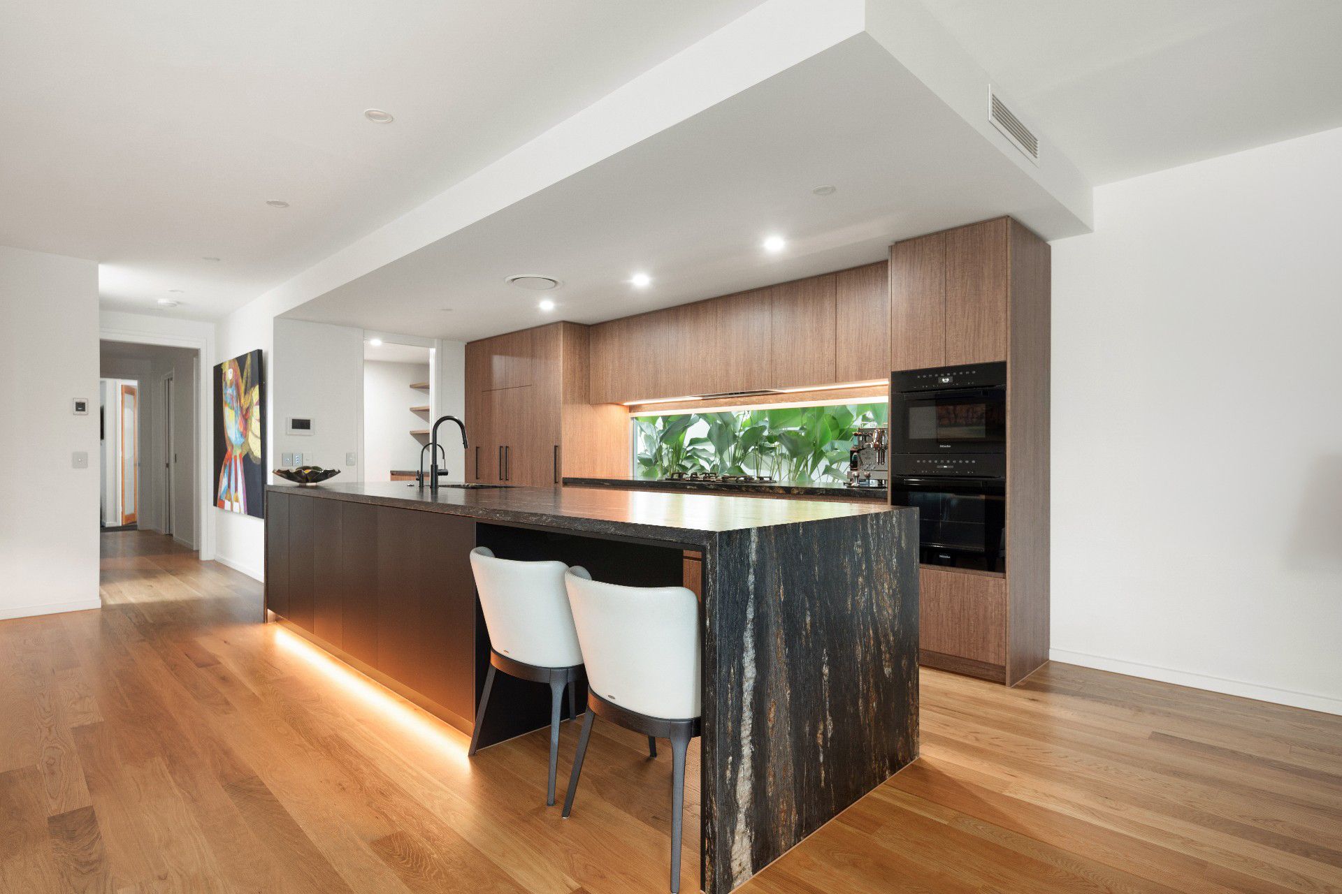 Modern kitchen with a dark granite island, wooden cabinets, and recessed lighting.