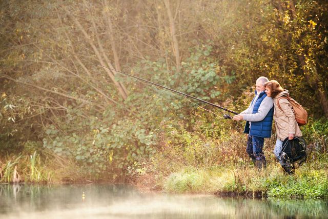 A man and a woman are fishing in a river.