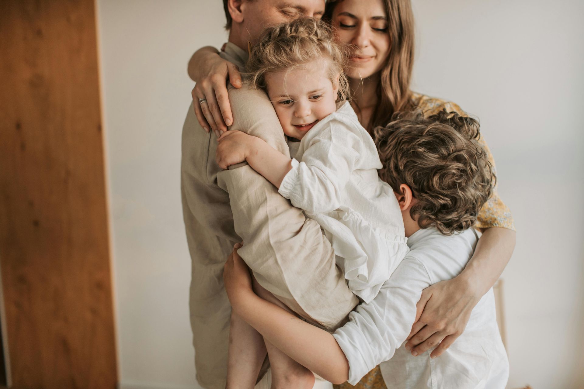 A family is hugging each other in a room.