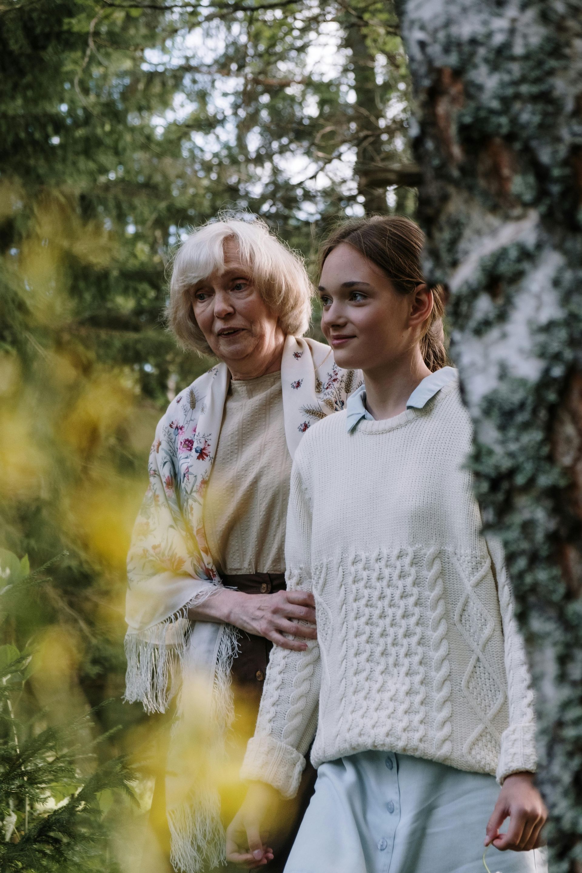 A woman and a girl are standing next to each other in the woods.