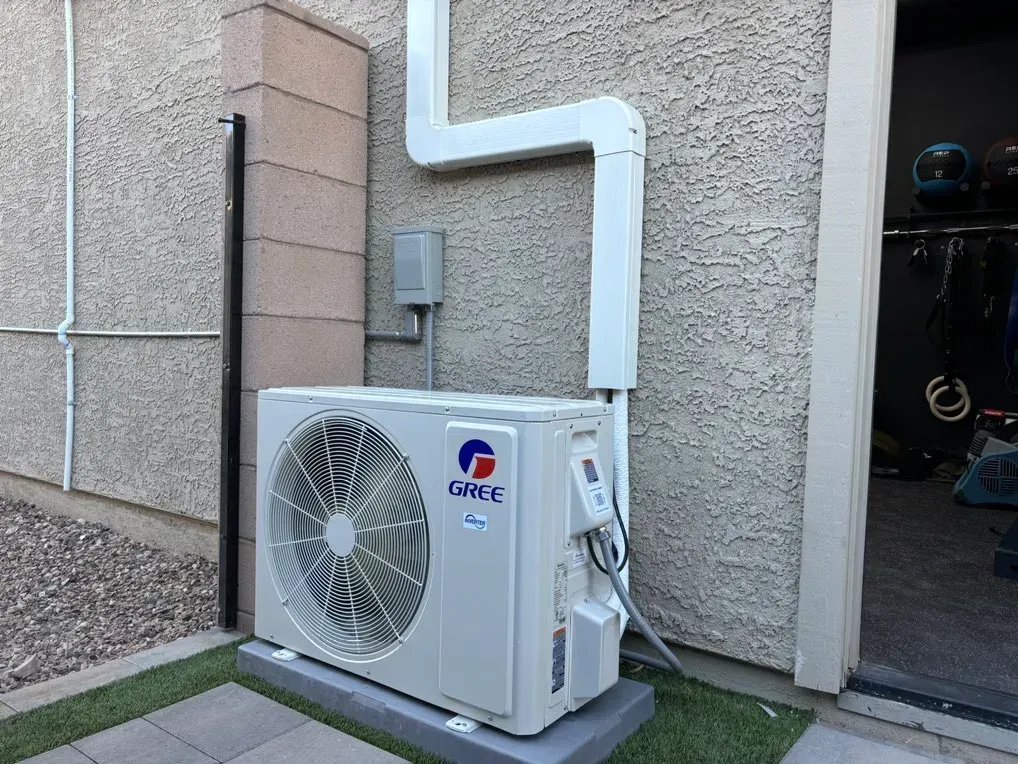 A white air conditioner is mounted on the side of a building.