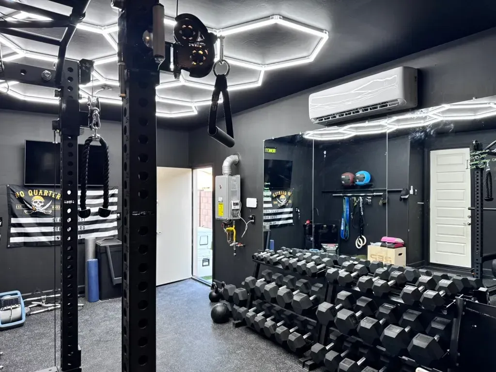 A gym with a lot of dumbbells and a large mirror.