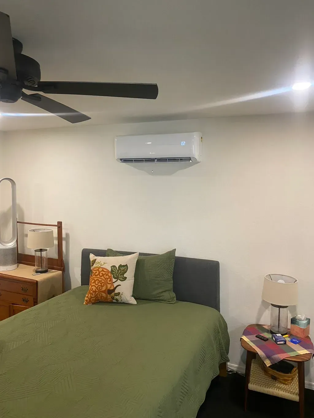 A bedroom with a bed , nightstand , lamp and ceiling fan.