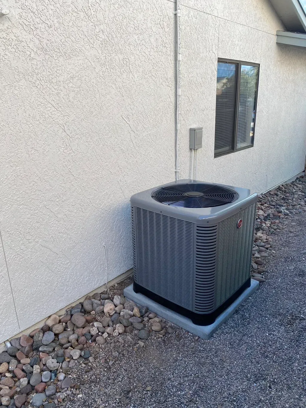 An air conditioner is sitting on the side of a building next to a window.