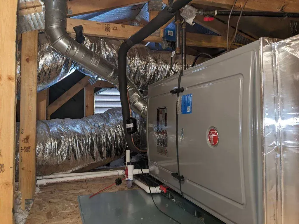 A room with a furnace and ducts hanging from the ceiling.