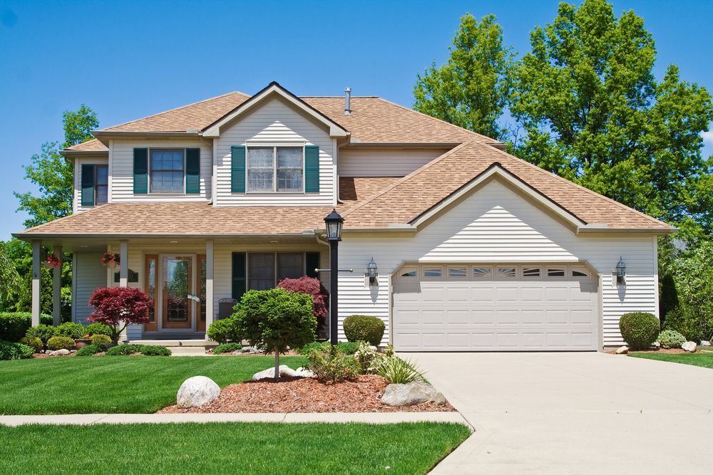 A white house with a brown roof and a white garage door