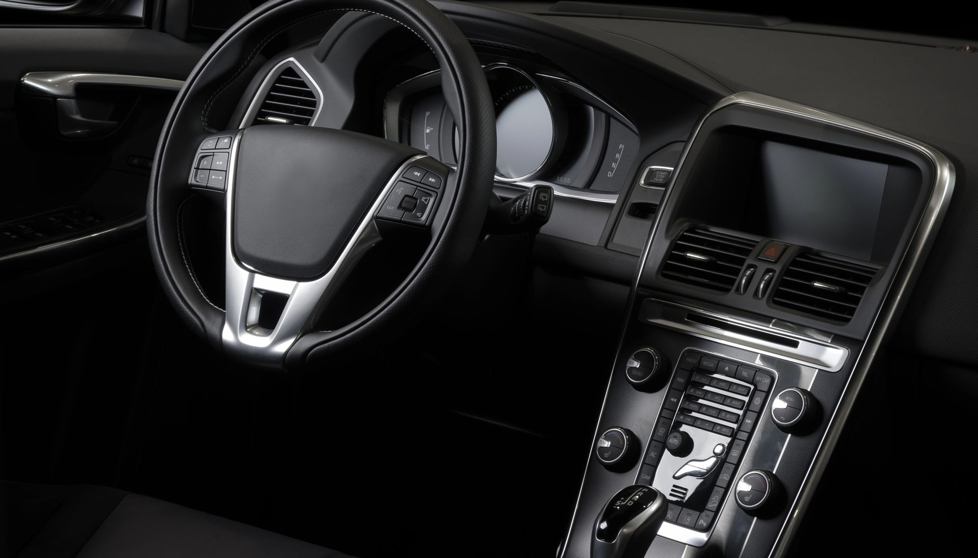 Interni dell'auto: cruscotto, volante, schermo di infotainment e comandi neri.