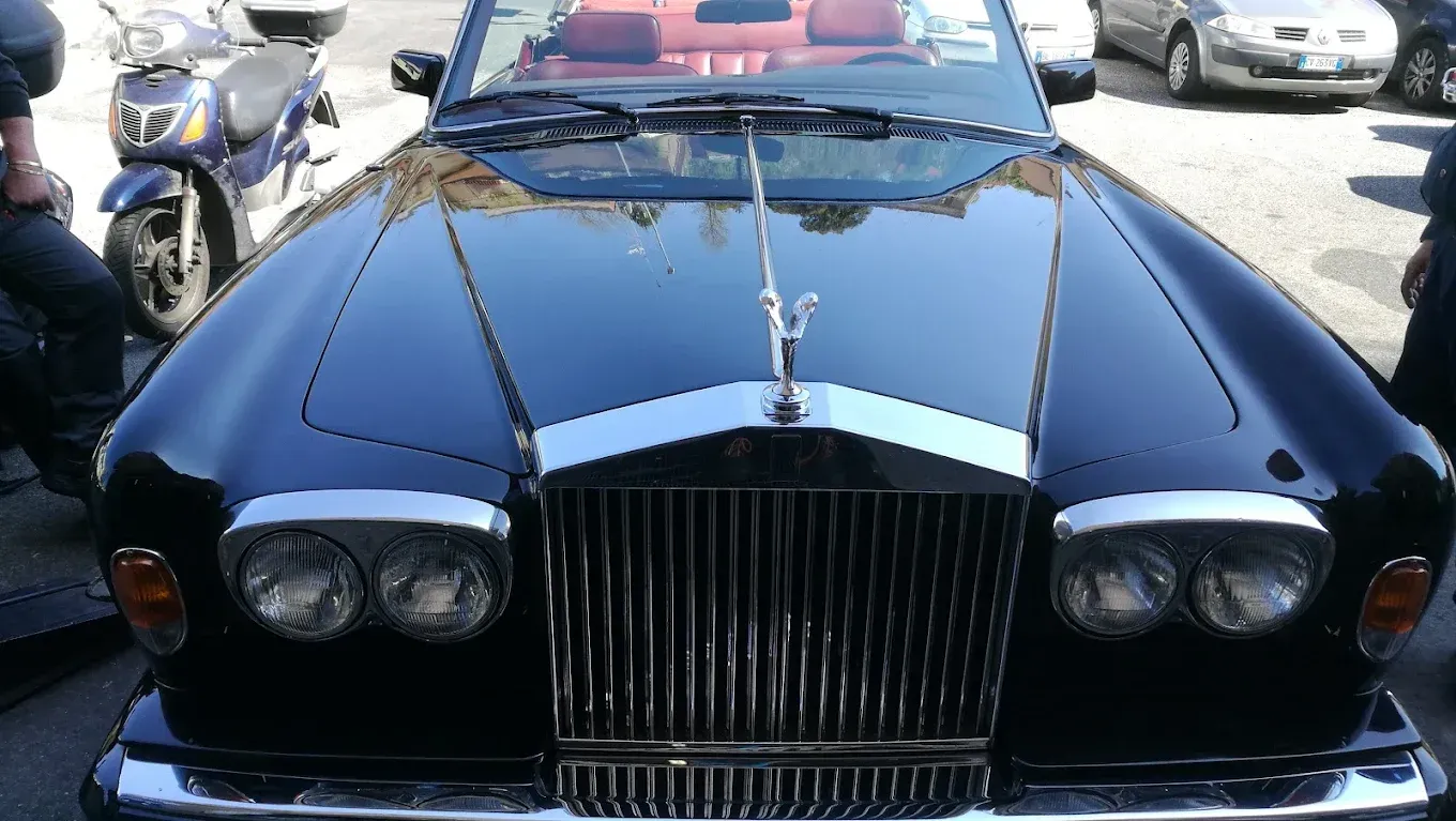 Rolls-Royce decappottabile nera con griglia cromata e fregio sul cofano. Interni rossi visibili.