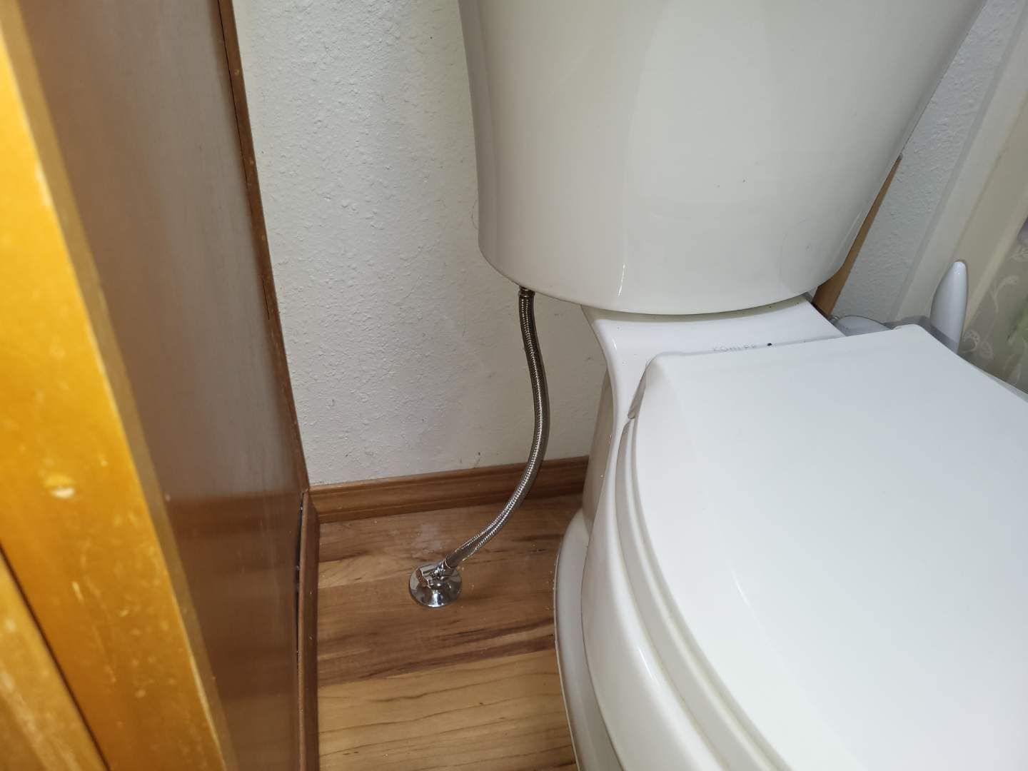 A close up of a toilet with a hose attached to it.