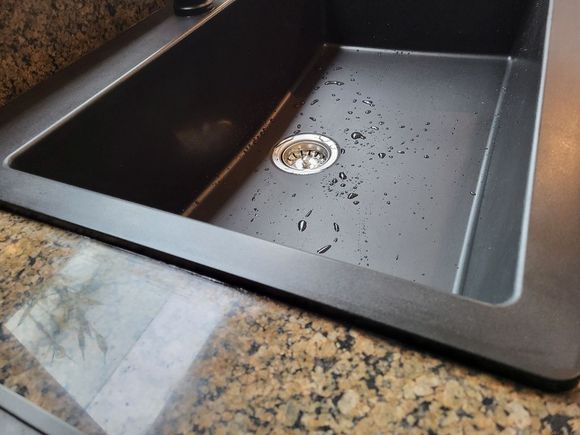 A sink with a black pipe underneath it