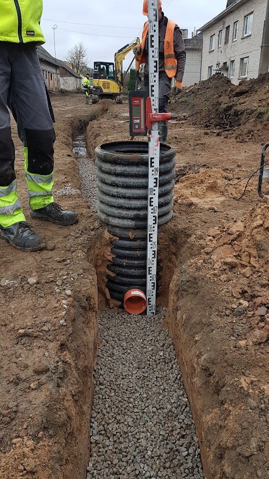 Vyras matuoja gylį tranšėjoje.