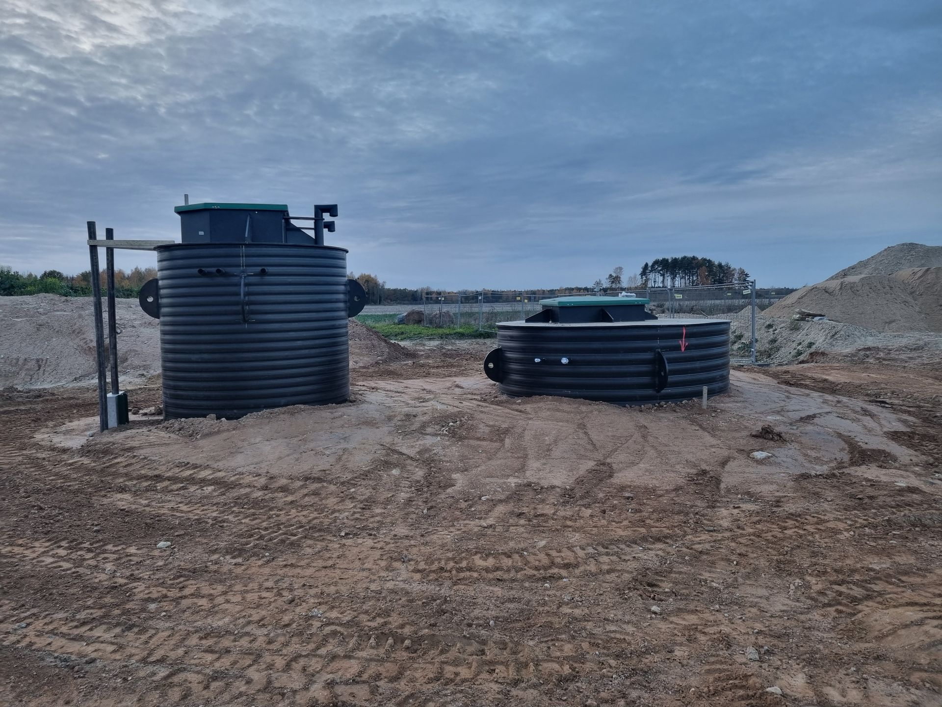 Du juodi konteineriai stovi lauko viduryje