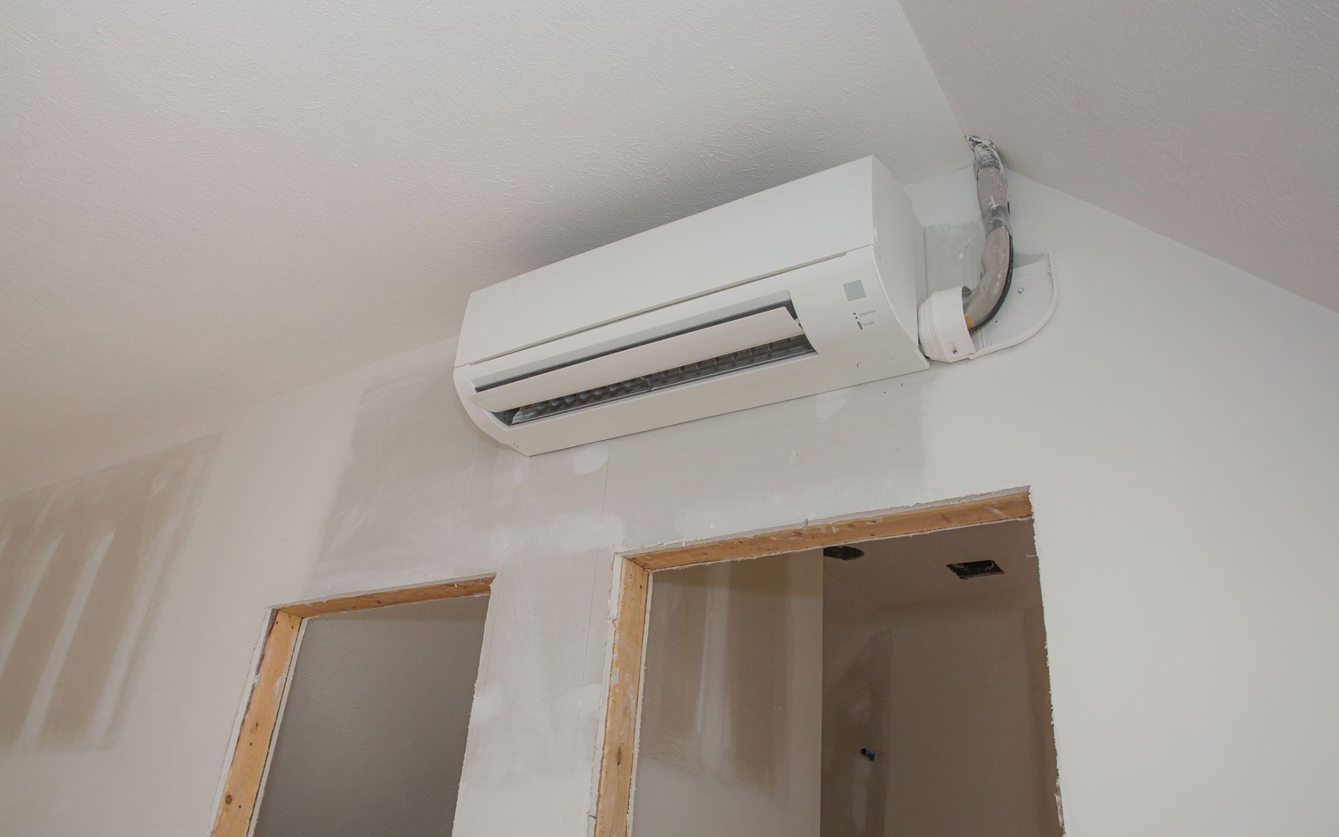 A white air conditioner is hanging from the ceiling in a room.