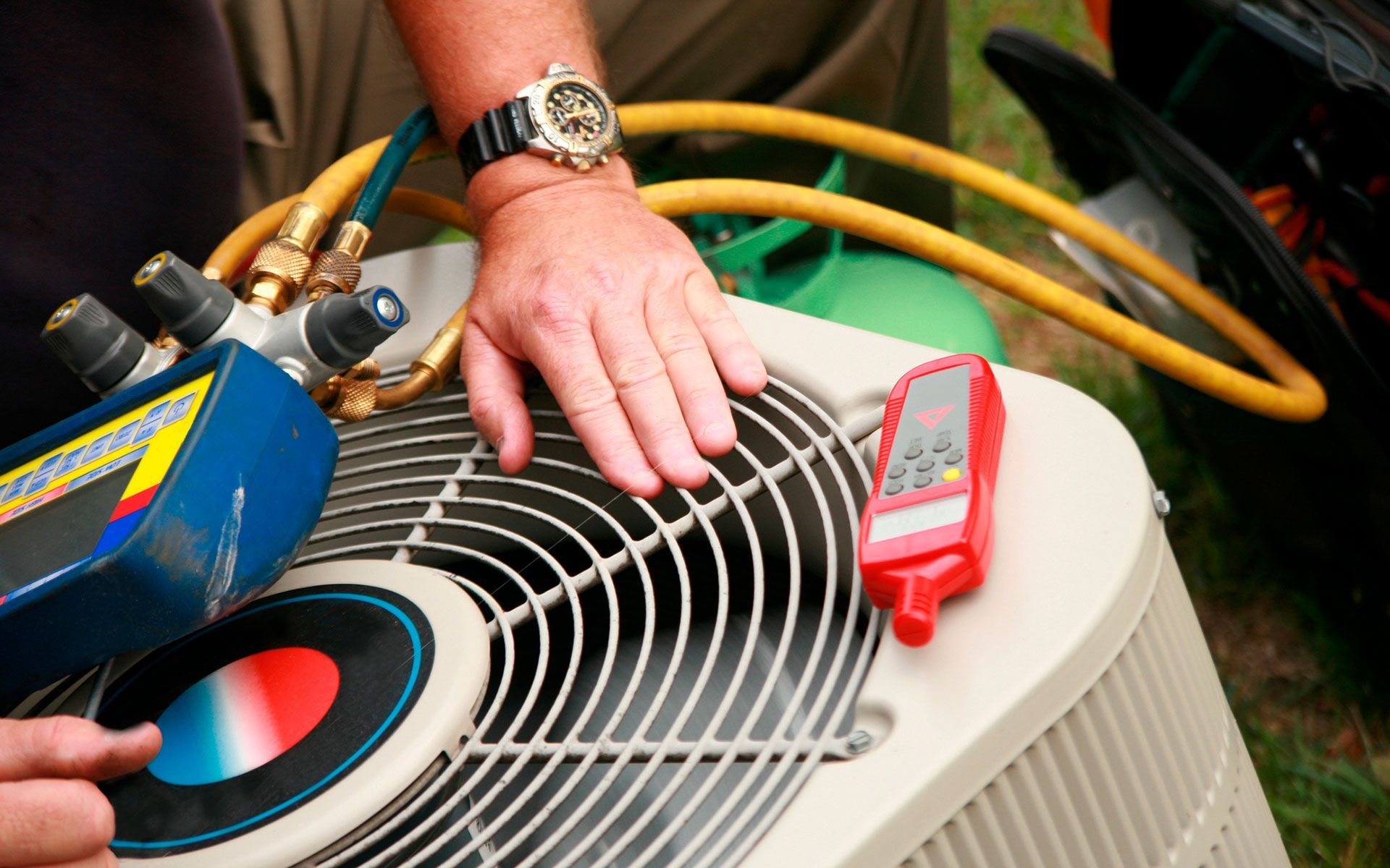 A man wearing a watch is working on an air conditioner