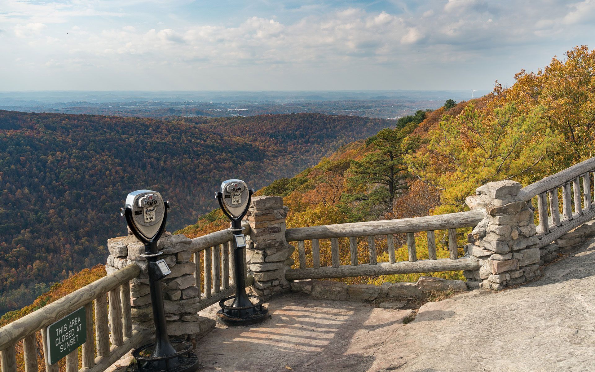 A view of a valley from a balcony with binoculars.