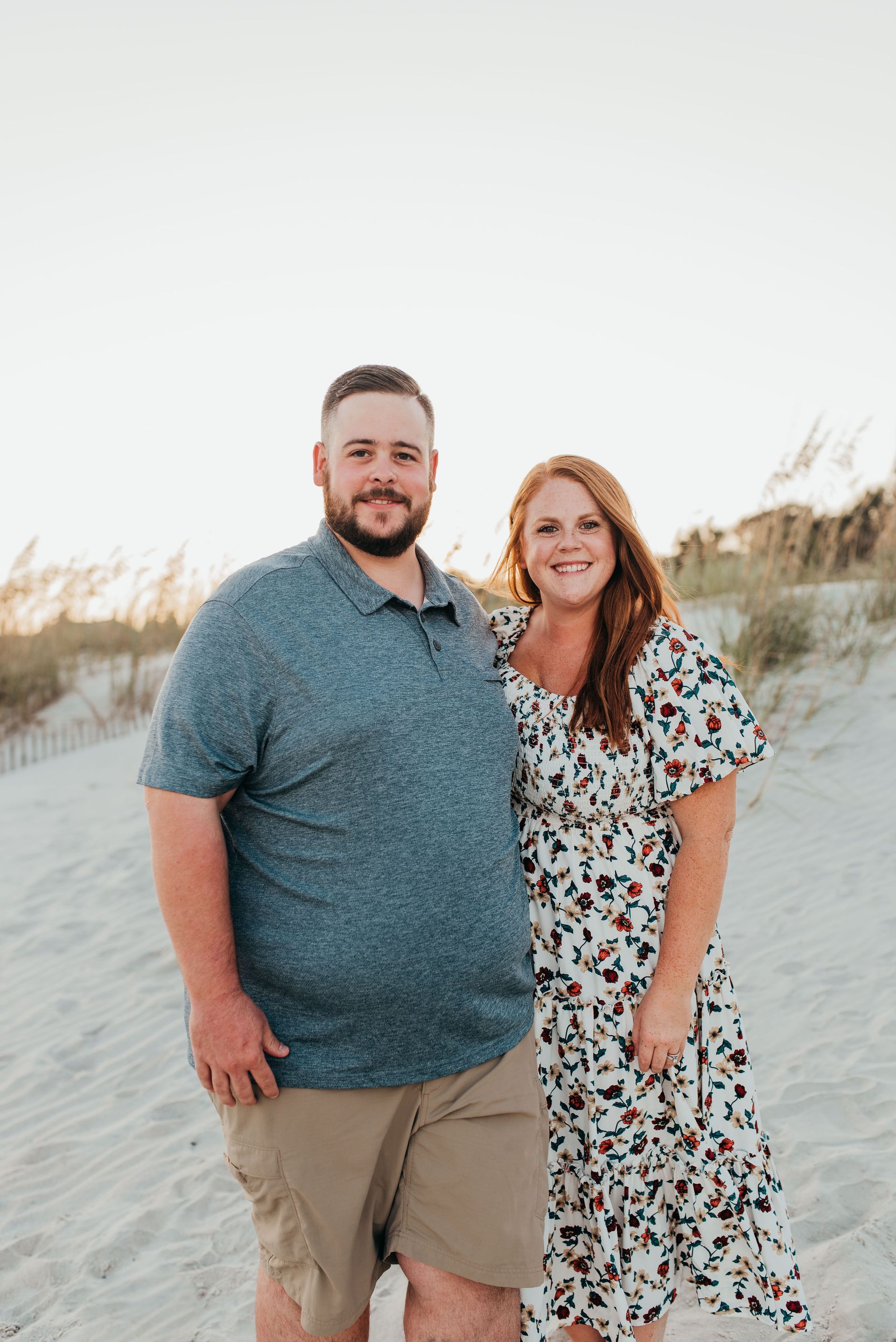 A man is kneeling down working on an air conditioner while looking at a tablet.
