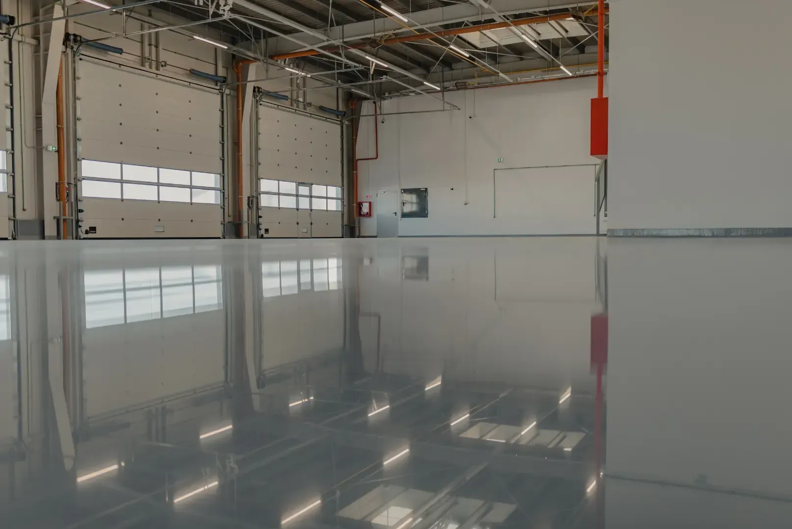 Glossy gray floor reflects a warehouse interior, showing doors, windows, and overhead lighting.