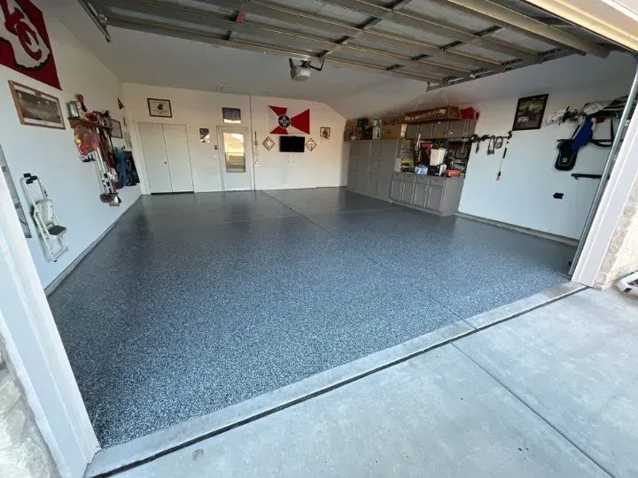 Garage with gray epoxy floor, cabinets, and open garage door.