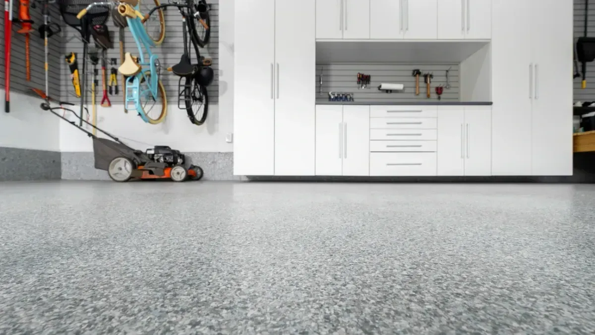 Shiny gray industrial floor reflecting the interior of a warehouse with open doors and bright lighting.
